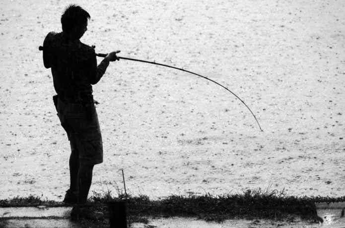 雨の中釣りをする男性