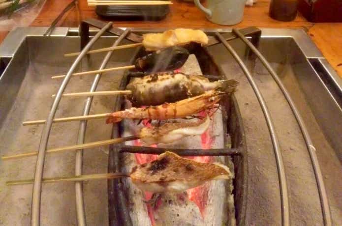 囲炉裏で食材を焼いている写真