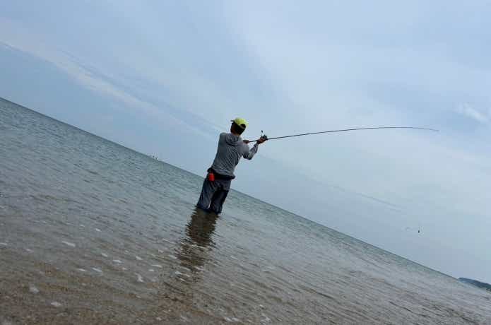水に浸かって投げる釣り人