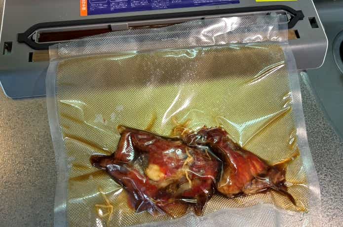 魚の煮付けを真空パックする様子